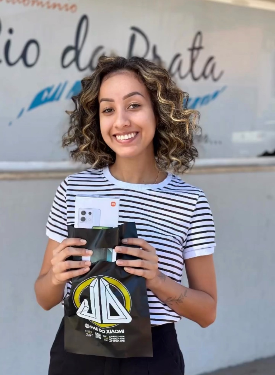 Cliente sorrindo e segurando um smartphone Xiaomi com a sacola do Pai do Xiaomi